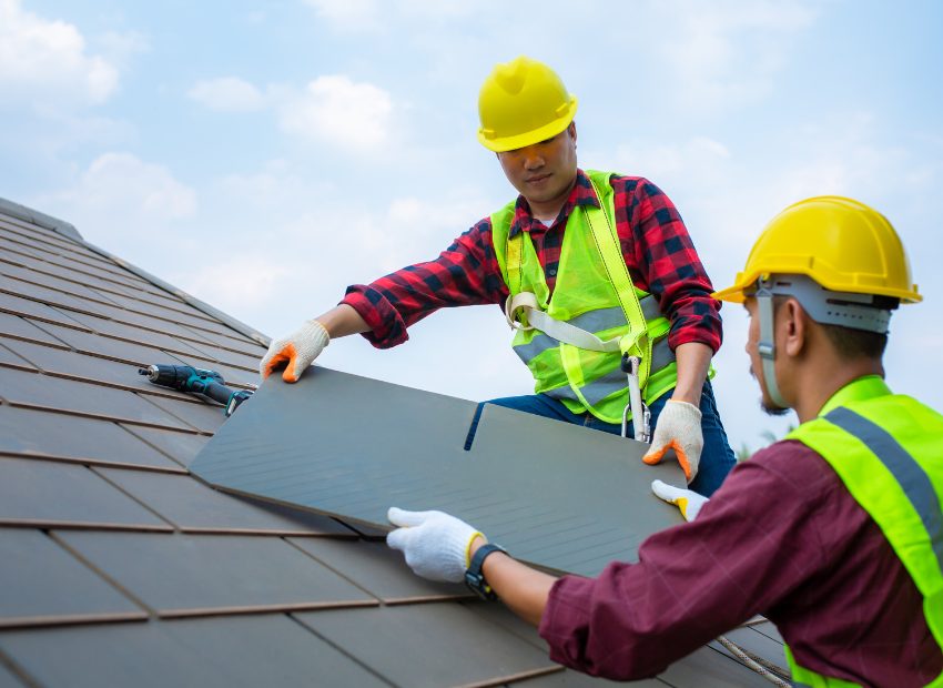 Two roofers in hard hats installing roofing panels