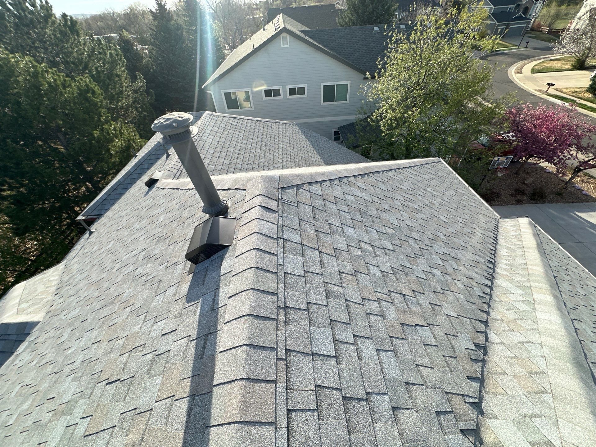 New ridge cap and vent flashing on a shingle roof in Arvada, Colorado.