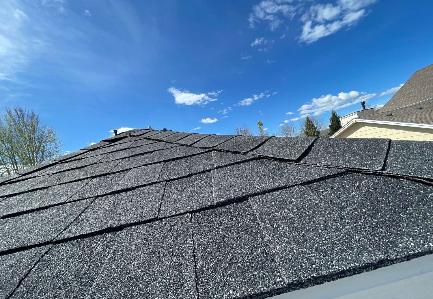Asphalt shingle roof against a blue sky in Longmont, CO