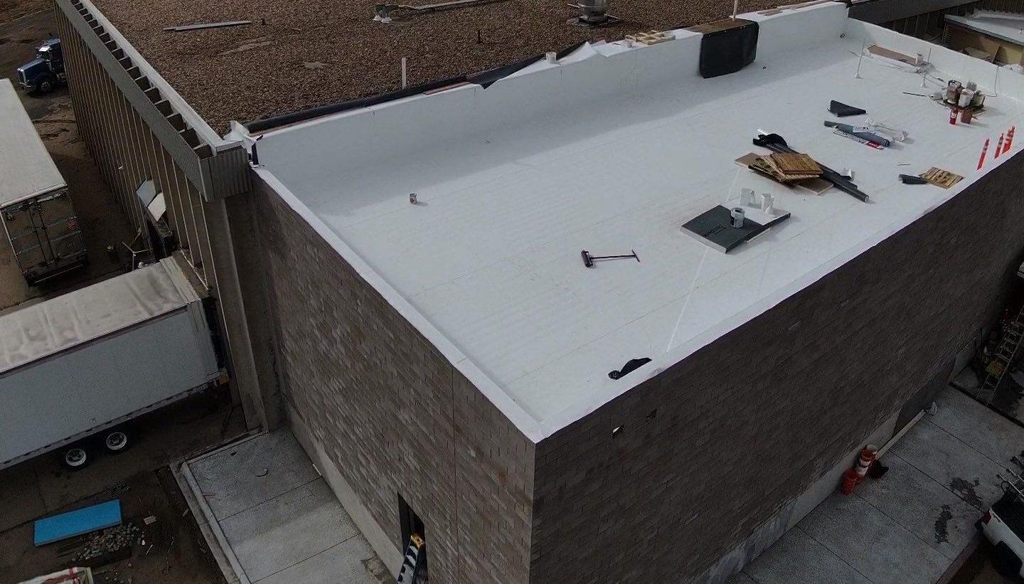 Aerial view of a white TPO roof being installed on a commercial building