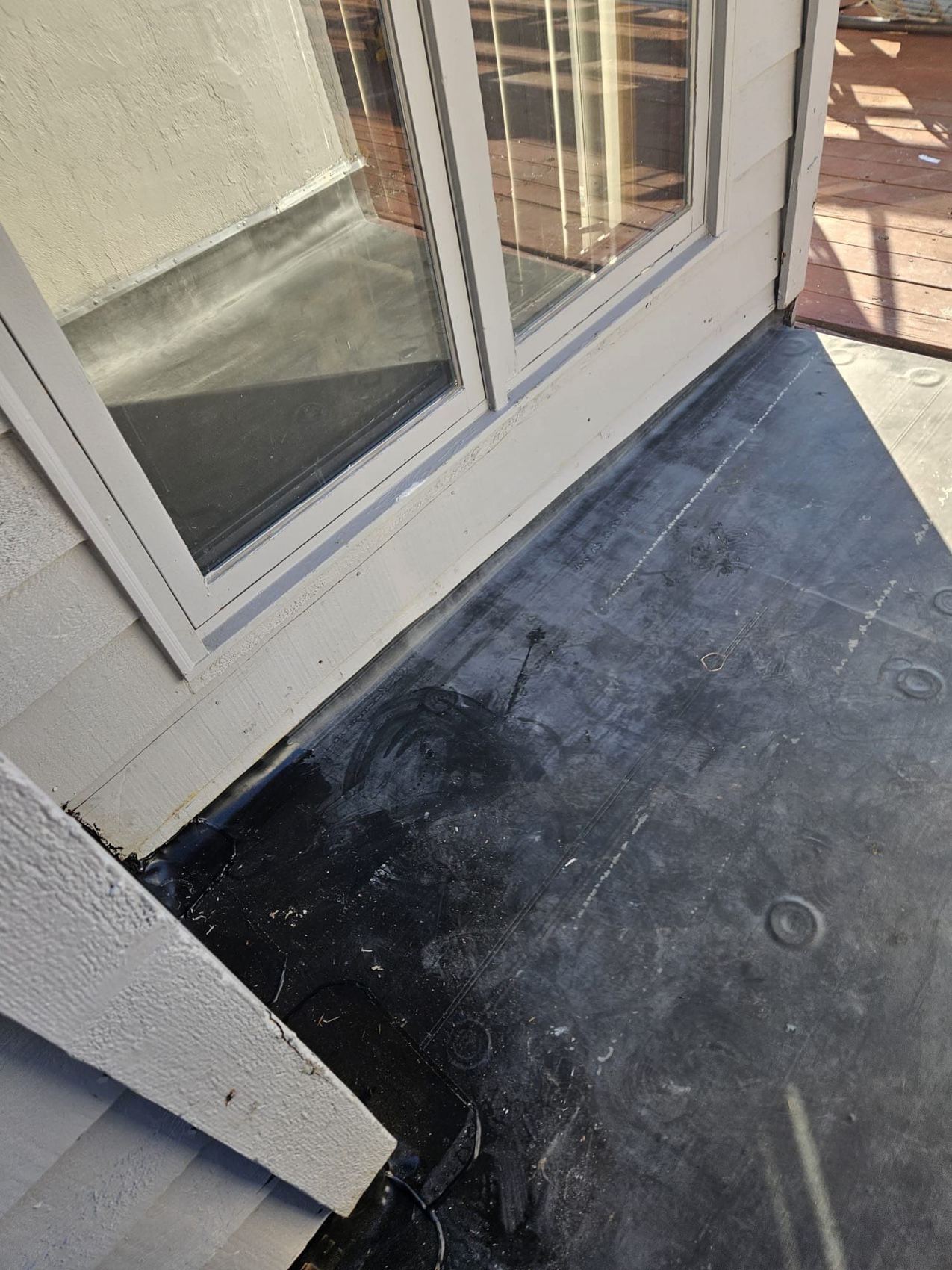 Fully adhered EPDM membrane at a door sill flashing detail
