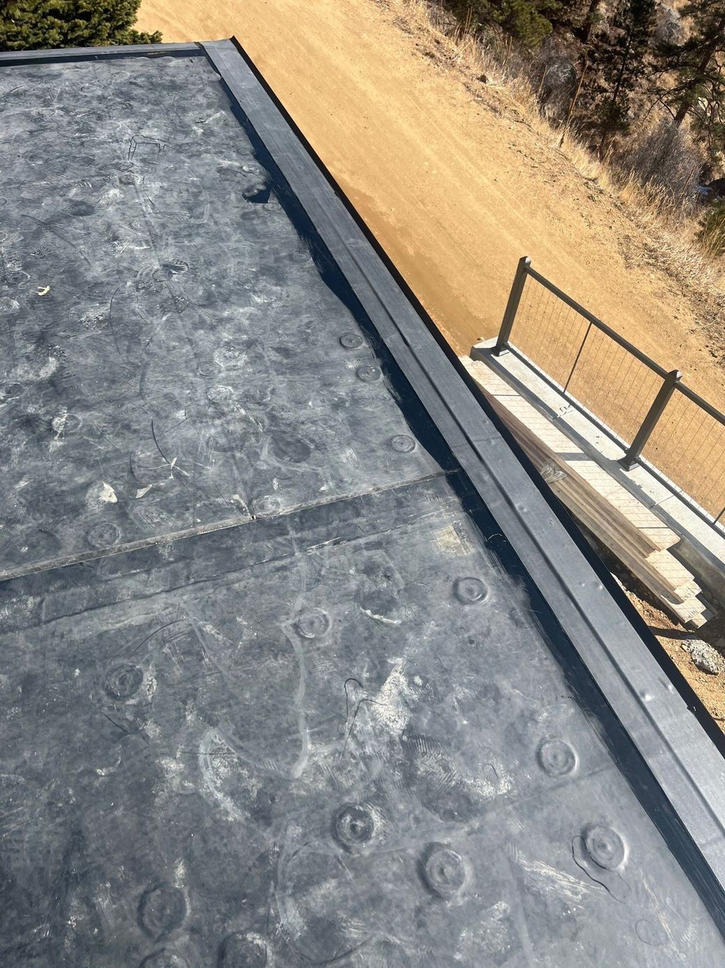 Finished fully adhered EPDM field with a lap seam along a metal roof edge