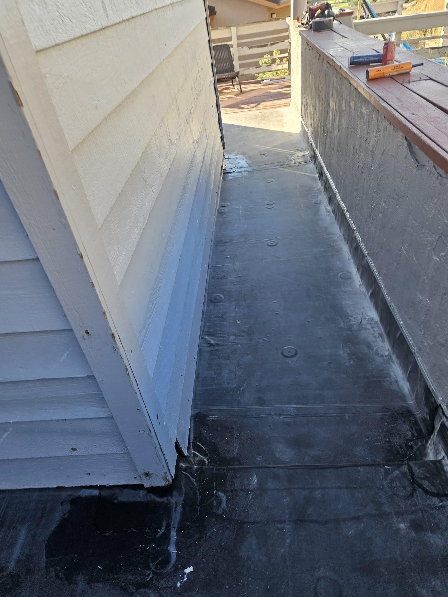 Fully adhered EPDM membrane on a deck walkway along a parapet wall