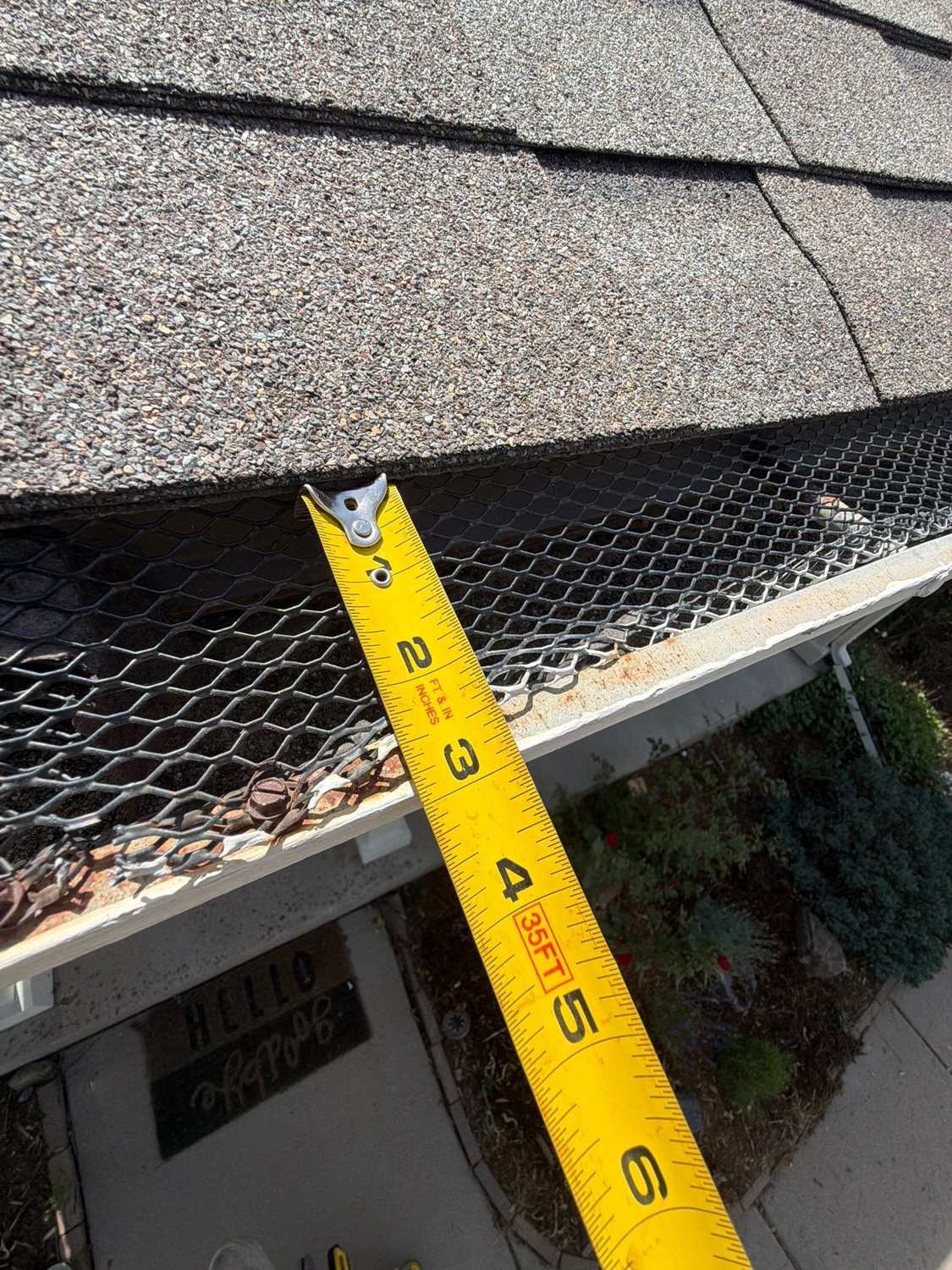 Measuring an old, debris-filled gutter before replacement in Littleton, CO