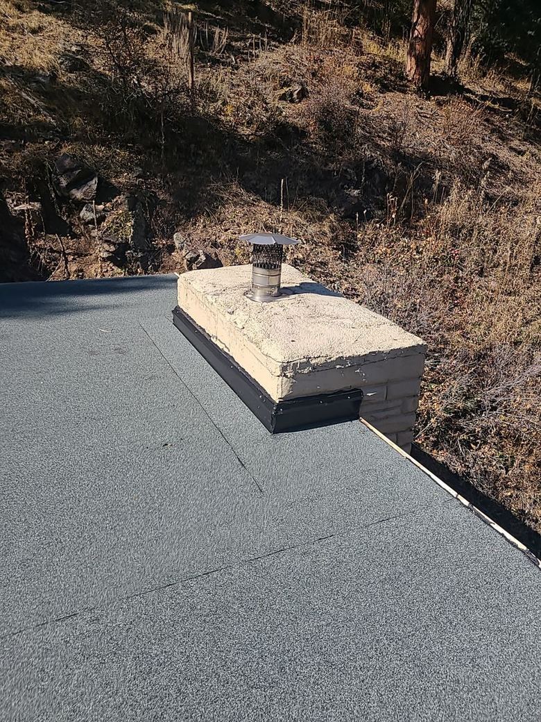 Modified bitumen roof flashed to a masonry chimney with metal counter-flashing