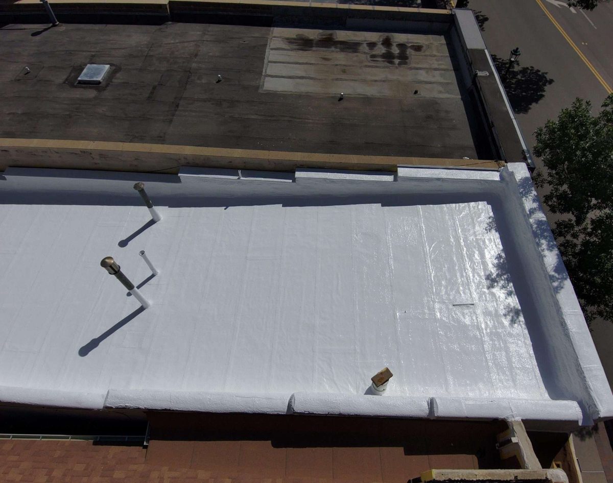 Overhead view of a finished white silicone roof coating with coated parapet walls