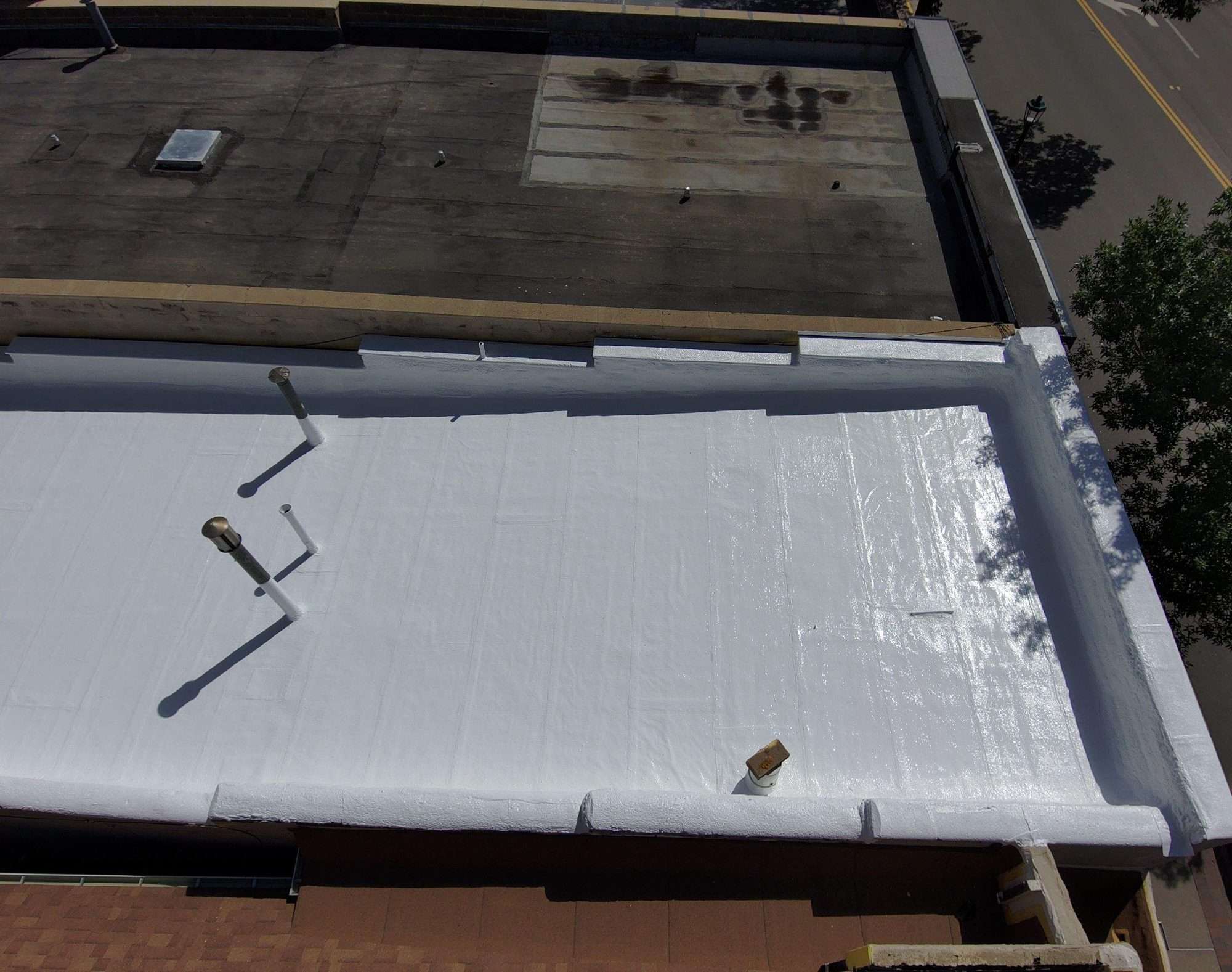 Overhead view of a finished white silicone roof coating with coated parapet walls