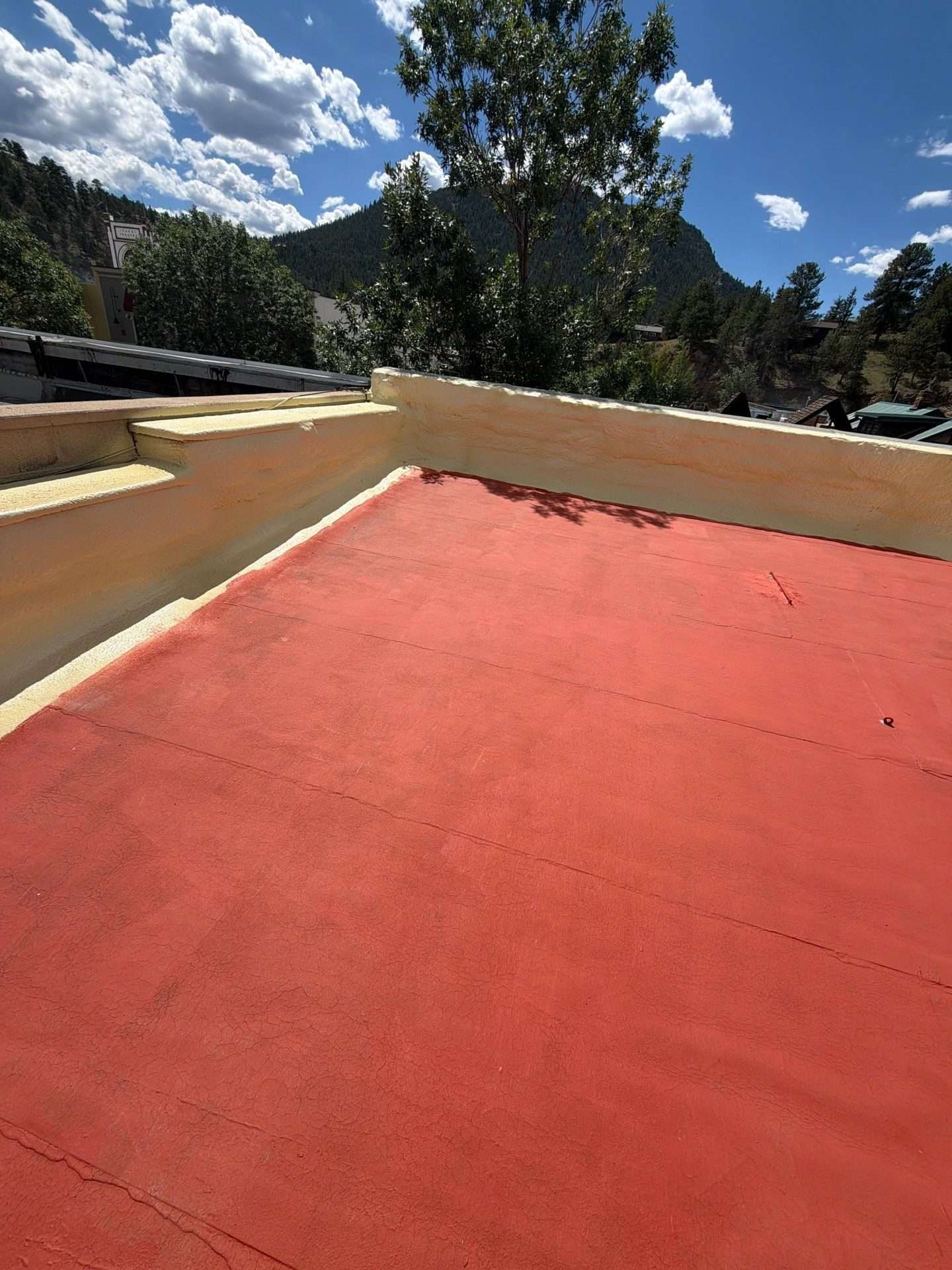 Red bleed-block primer applied to a low-slope roof before the silicone roof coating