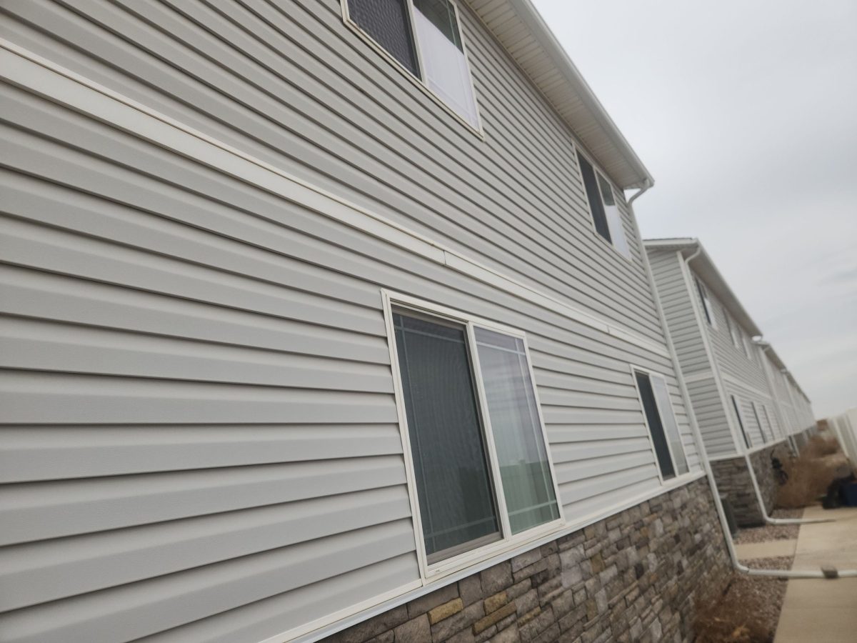 New vinyl lap siding above a stone base after a siding replacement on a multifamily building in Colorado.