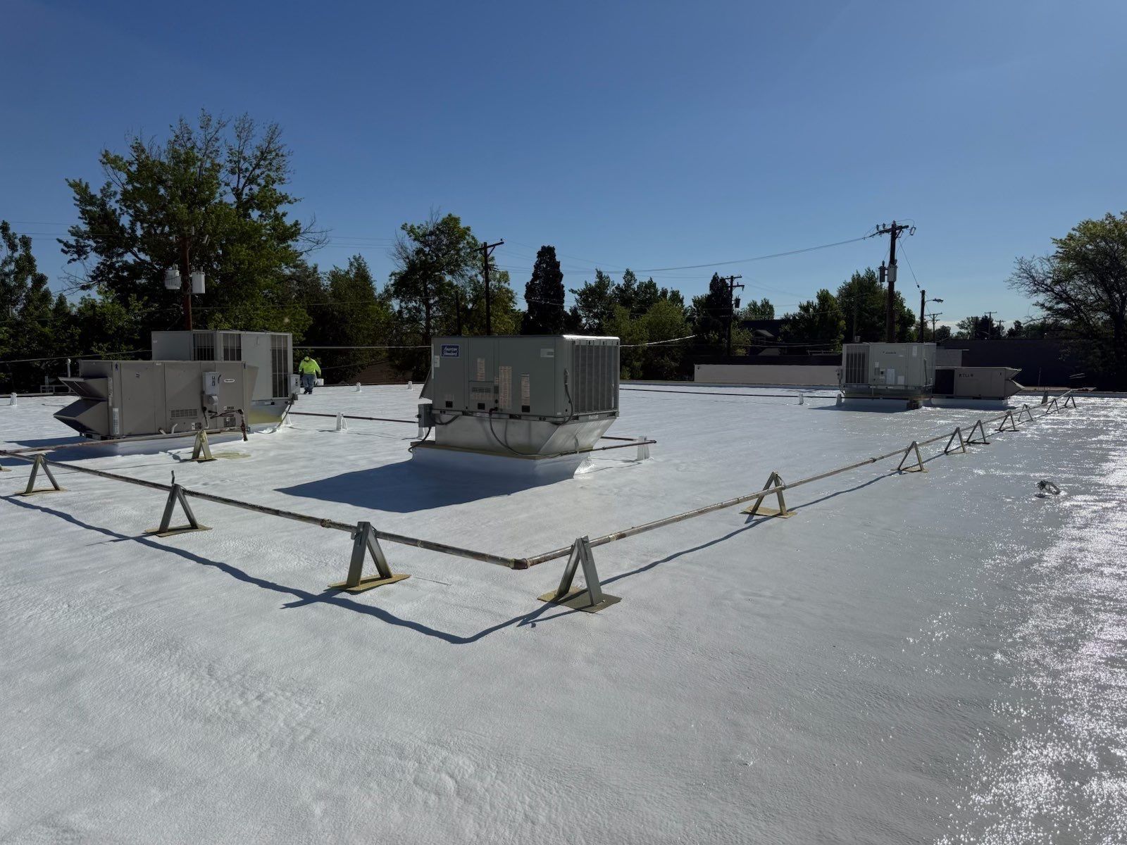 Finished white silicone coating over spray foam on a commercial roof with rooftop units