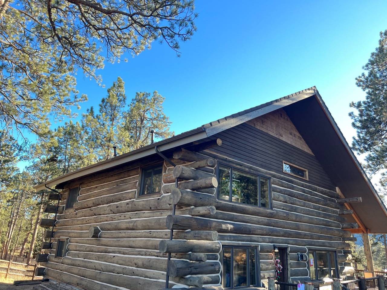 Timberwood stone-coated steel roof on a two-story log home gable with steel rake trim