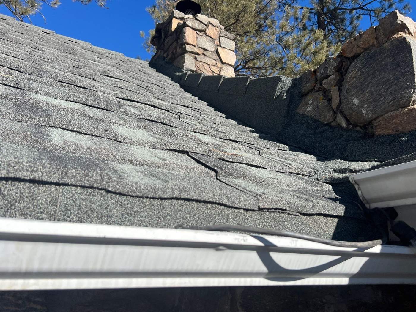 Iron Wood stone-coated steel panels and flashing at a stone chimney above the gutter