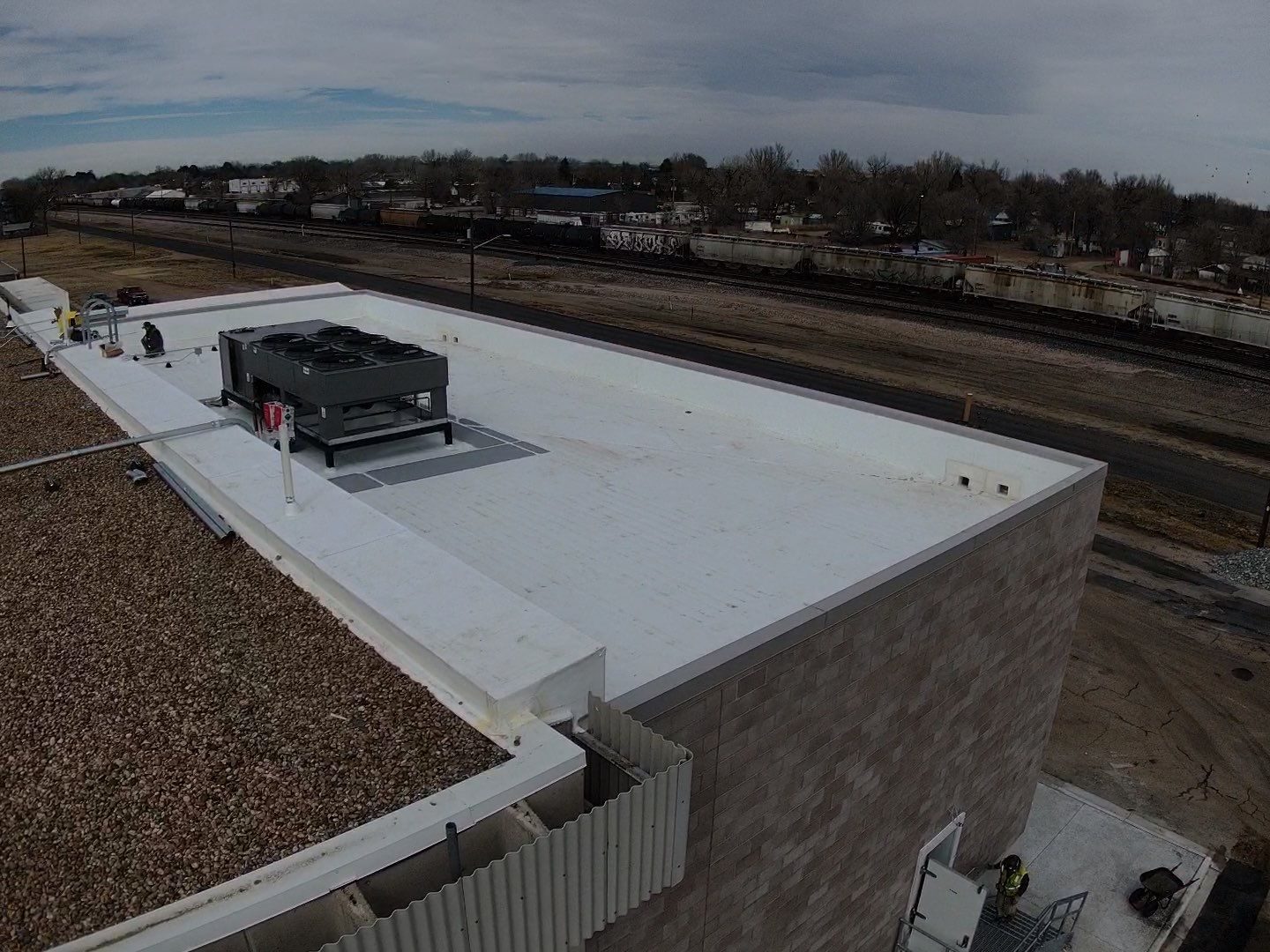 Finished white TPO roof with a rooftop unit and parapet edge on a commercial building in Colorado.