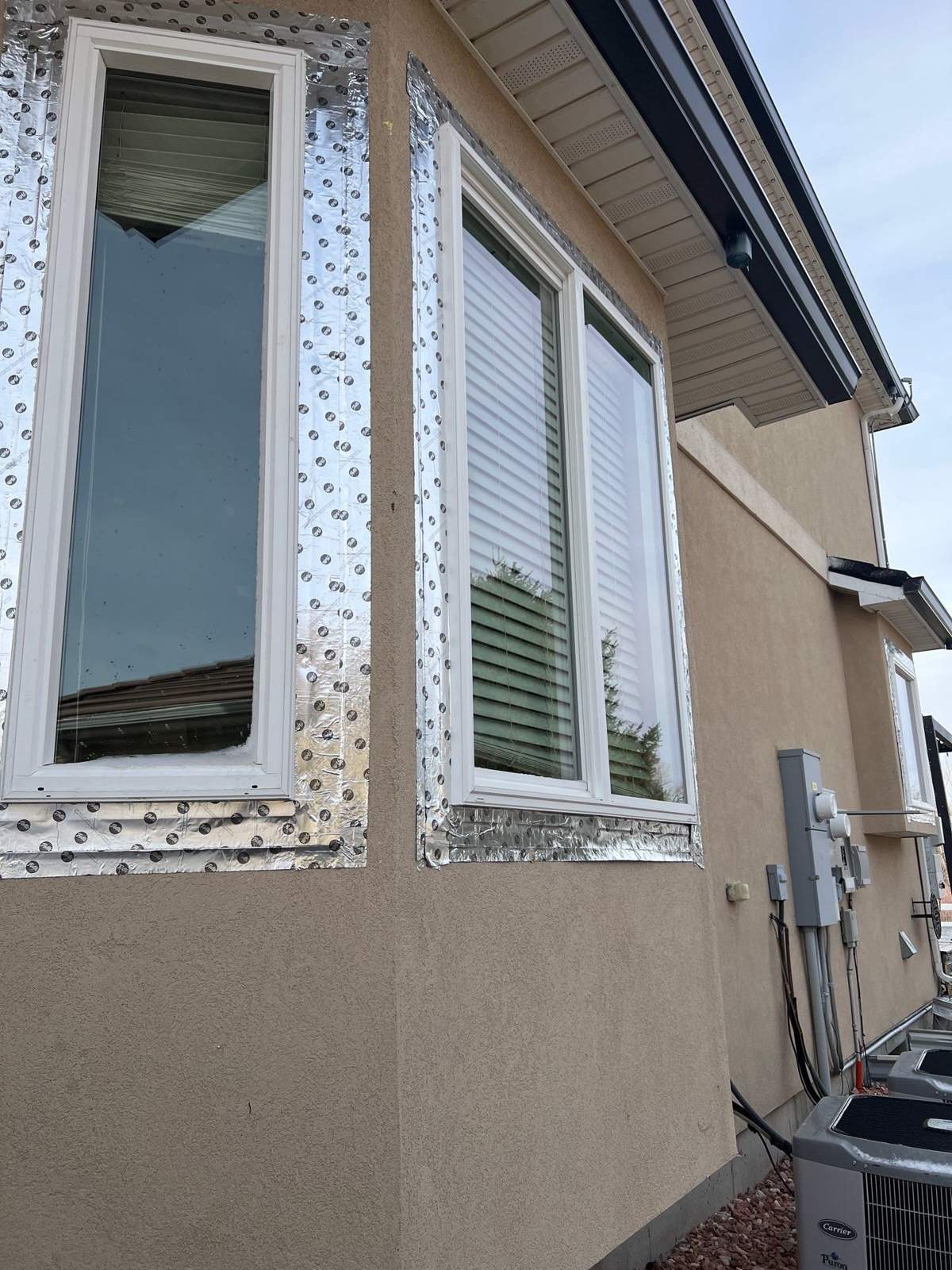 New white vinyl windows set in stucco with flashing tape before patching