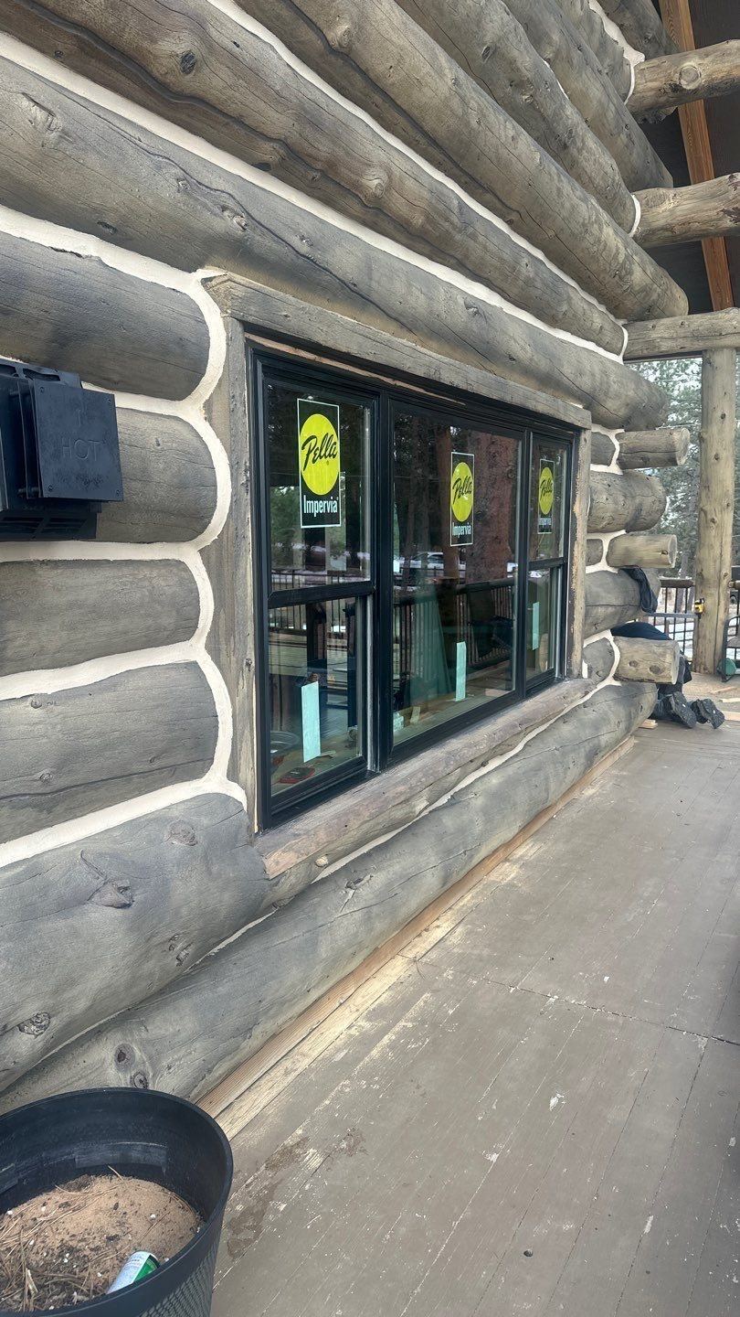 New black-clad windows being installed in a log home