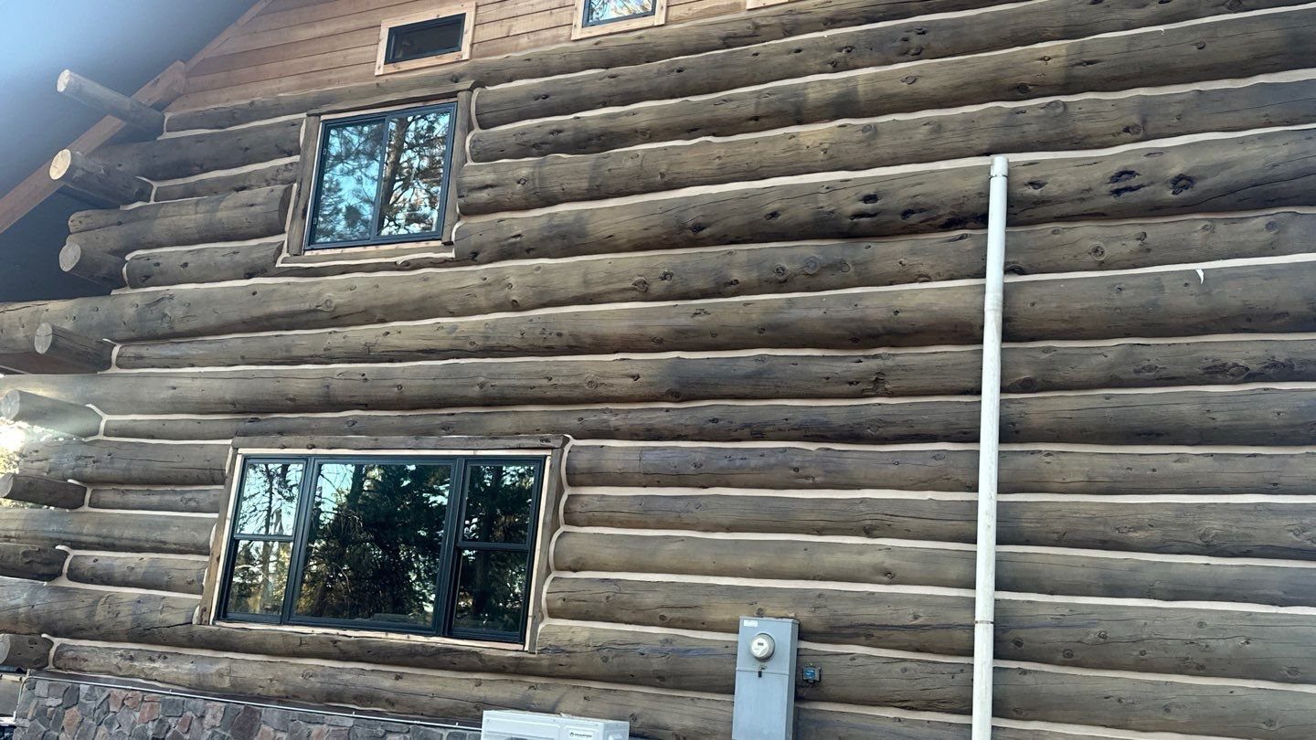 After window replacement: new black-framed windows on a log home