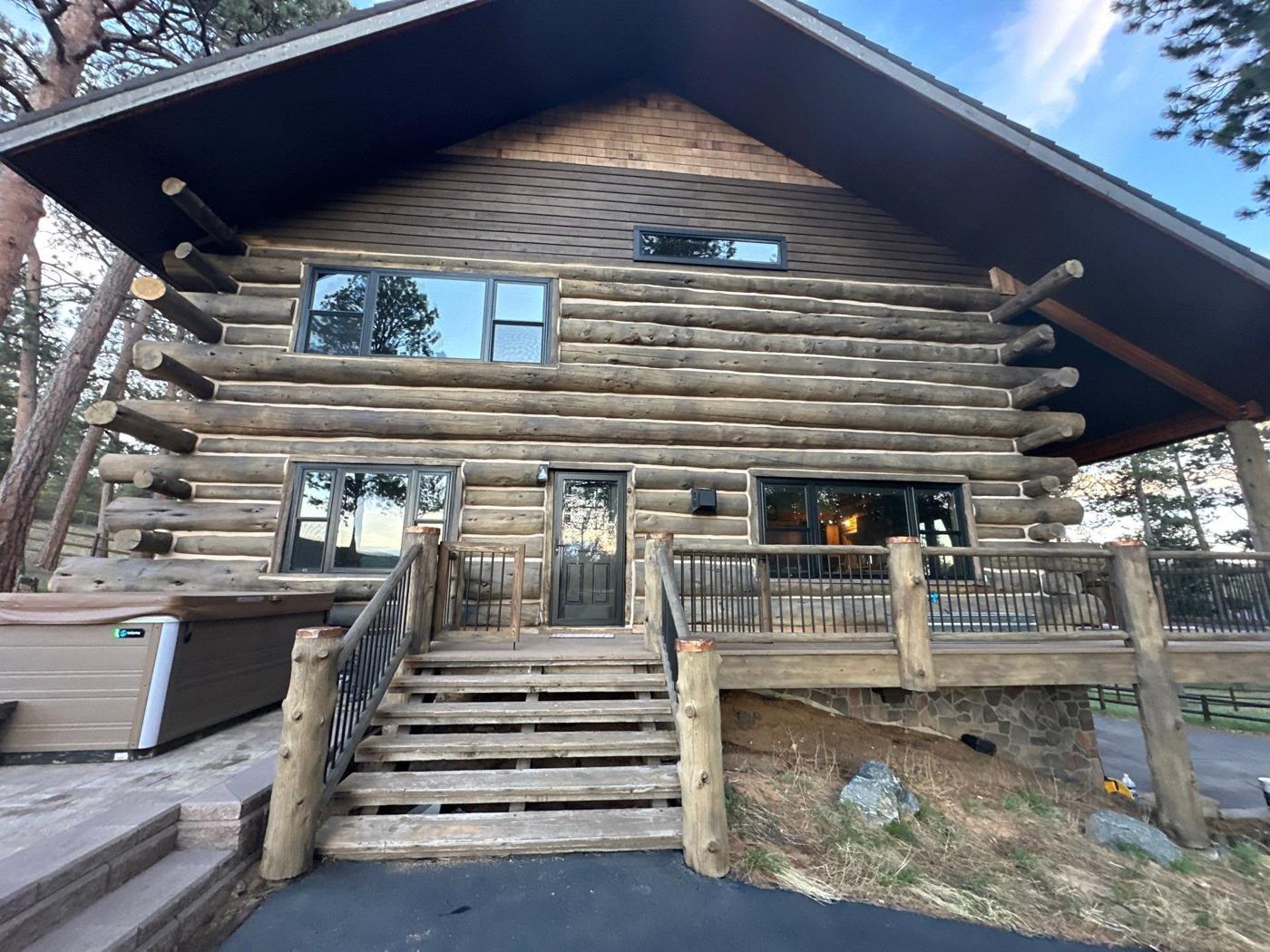 Log home front with new black windows across both floors