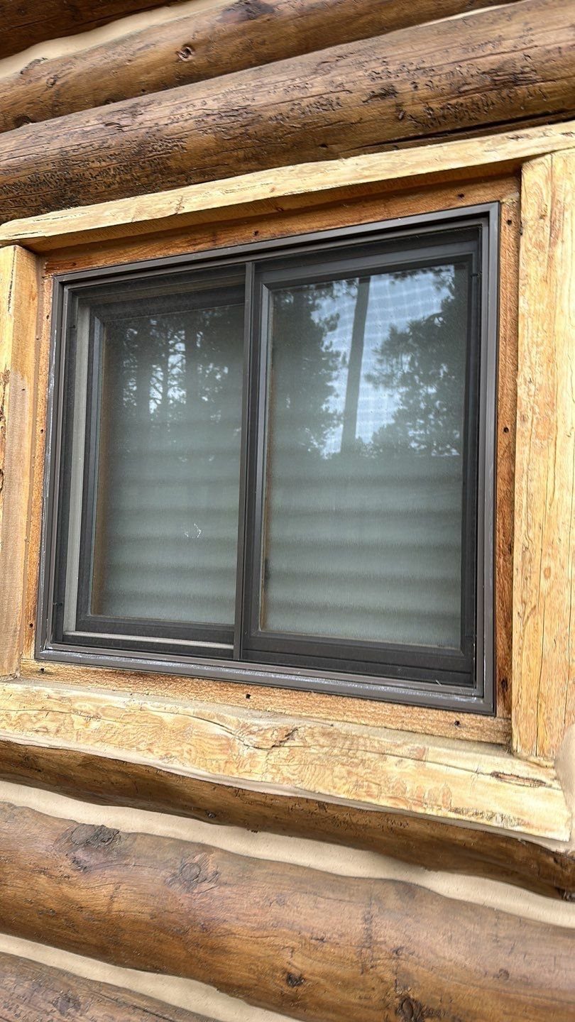 Before window replacement: aging dark slider window in a log wall