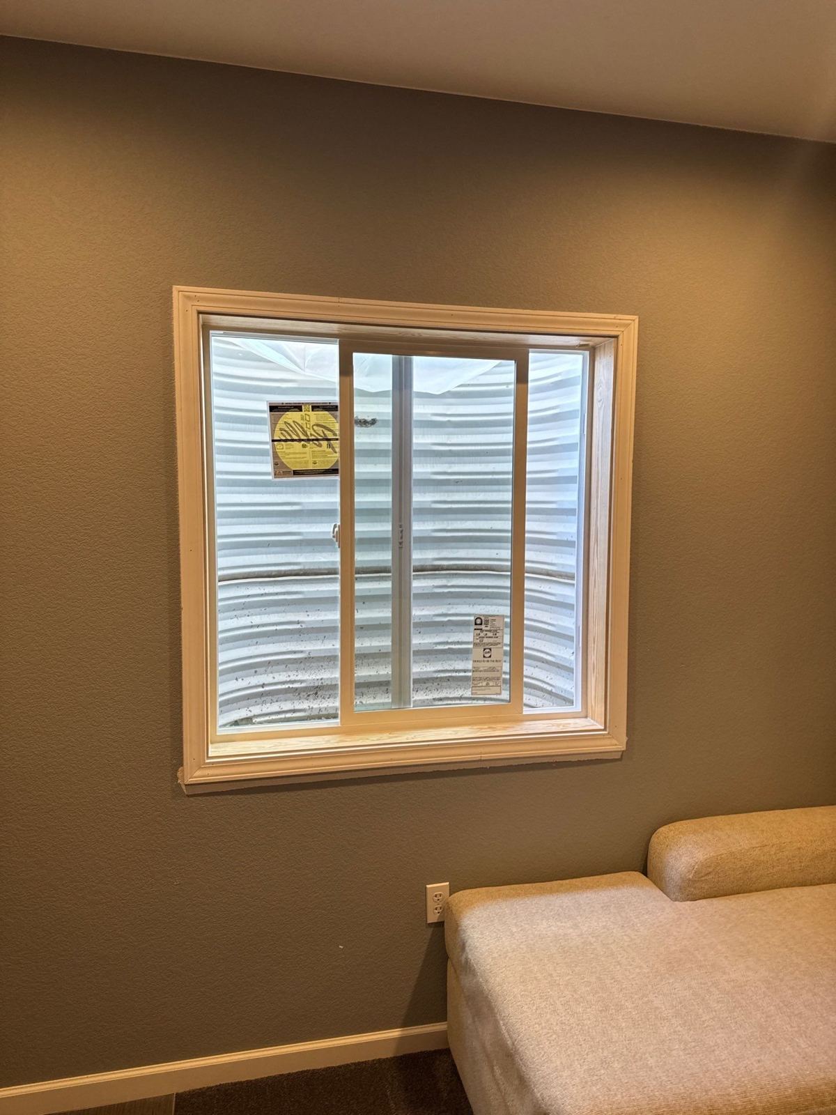 New white vinyl slider window in a basement egress well with wood trim
